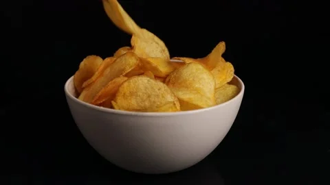 Hand takes chips from a plastic bowl on a black background Video stock 228922734