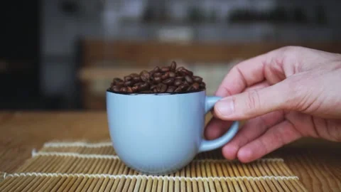 Hand takes a coffee cup full of coffee beans 库存影片 150401912