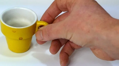 Hand takes cup of yellow coffee on a white background Video stock 87874950
