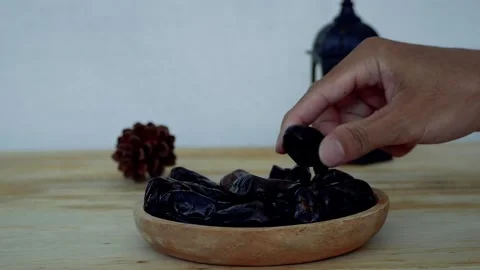 Hand takes dates from plate with dramatic light. 4K. Stock-Footage 235400924