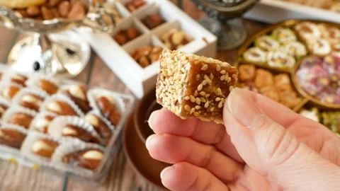 Hand takes eastern sweets with nuts,dates, candy in metal vase on wooden back Stock Footage 145122635