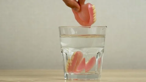 Hand takes false teeth in glass of water Stock-Footage 253463106