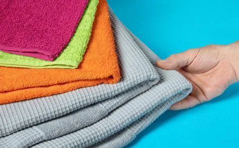 Hand takes a fresh towel from a stack of colorful towels Stock Photos
