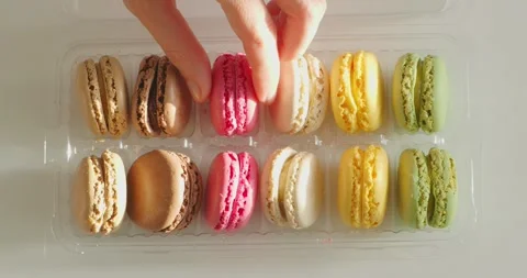 Hand takes macarons from plastic box, french dessert. Close-up. Stock Footage 243398522
