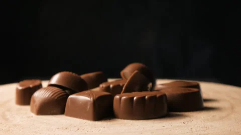 The hand takes one candy. Chocolate candies on a black background Stock Footage 263340210