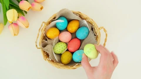 Hand takes one egg from a wicker basket with multi-colored Easter eggs Stock Footage 331499535
