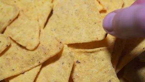 The hand takes one nachos, a macro static shot. The concept of unhealthy and Stock Footage 125712180