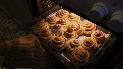 The hand takes out a baking tray with buns to check their readiness Stock Footage 221966985