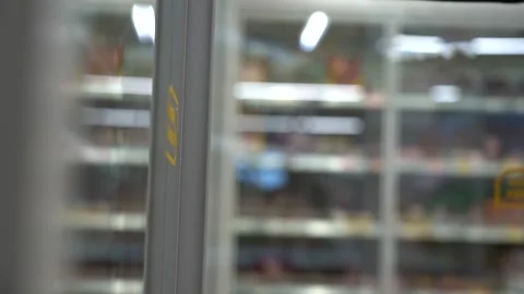 A hand takes a plastic bottle from a refrigerated shelf in a store. Video stock 165992880