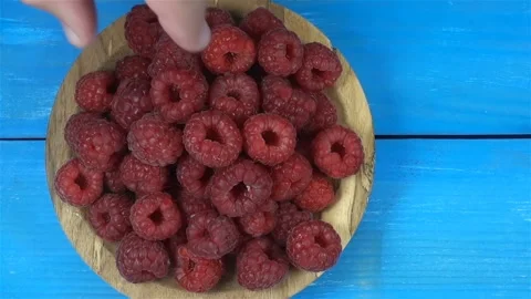 The hand takes a raspberry from a plate filled with berries. Stock Footage 135915265