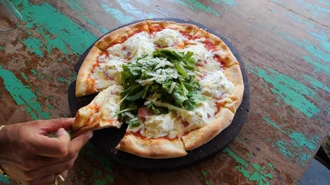 Hand takes a slice of fresh pizza on a rustic wooden table, Bali Stock Footage 140253902
