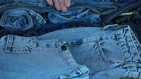 Hand takes in slow motion folded jeans Stock Footage 130877016