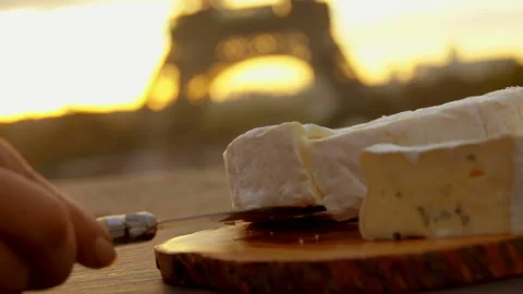 Hand takes a soft brie cheese next to Eiffel Tower Video stock 122995886
