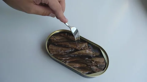 Hand takes a sprat from a can with a fork Stock Footage 224513887