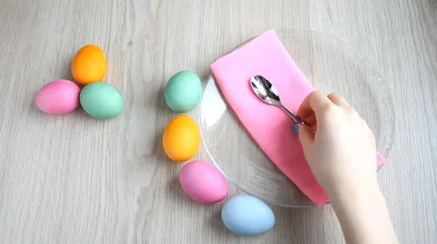 Hand takes a teaspoon from the table. On the table are colored easter eggs. Stock Footage 61569435