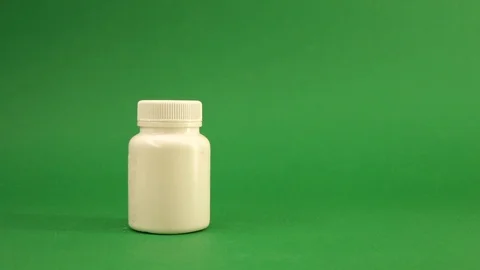 Hand takes white packaging with pills standing on a green background Stockbeeldmateriaal 122944722