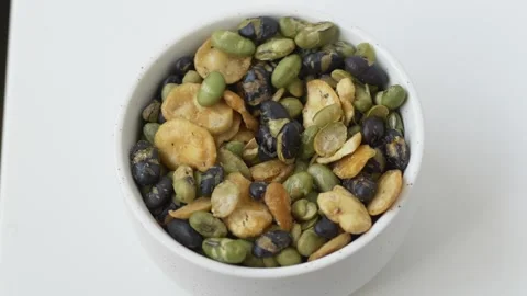 Hand taking bean snack from white bowl rich in natural protein and dietary fiber Video stock 331010326