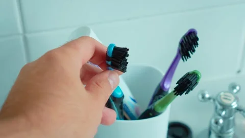 Hand taking blue toothbrush from holder with colorful dental care supplies Stock Footage 345125833