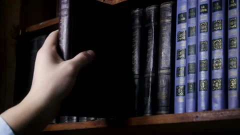 Hand taking book from the shelf. Hand selecting book from a bookshelf. Video stock 123530495