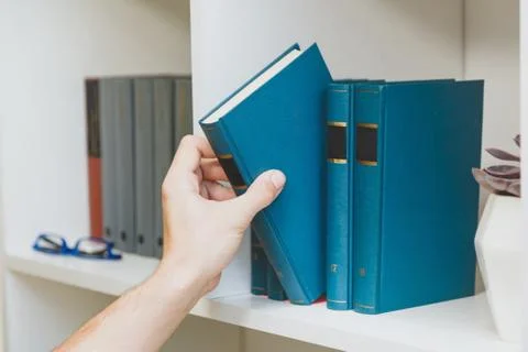 Hand taking book from the shelf Stock Photos