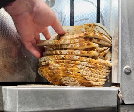 Hand Taking Bread from Slicing Machine 스톡 사진