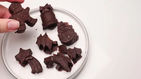A hand taking a chocolate candy shaped like festive figures from a white pl.. Stock Footage 321833787