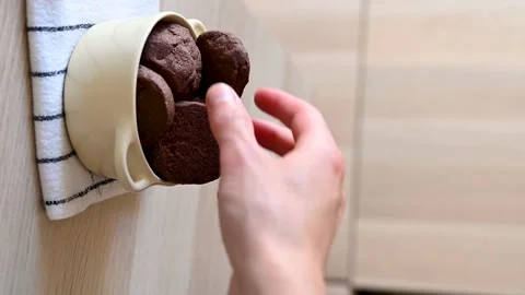 Hand taking a cocoa cookie from a bowl Stock Footage 219963108