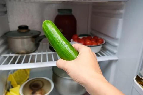 A hand taking a cucumber out of the fridge in order to lose weight Stock Photos