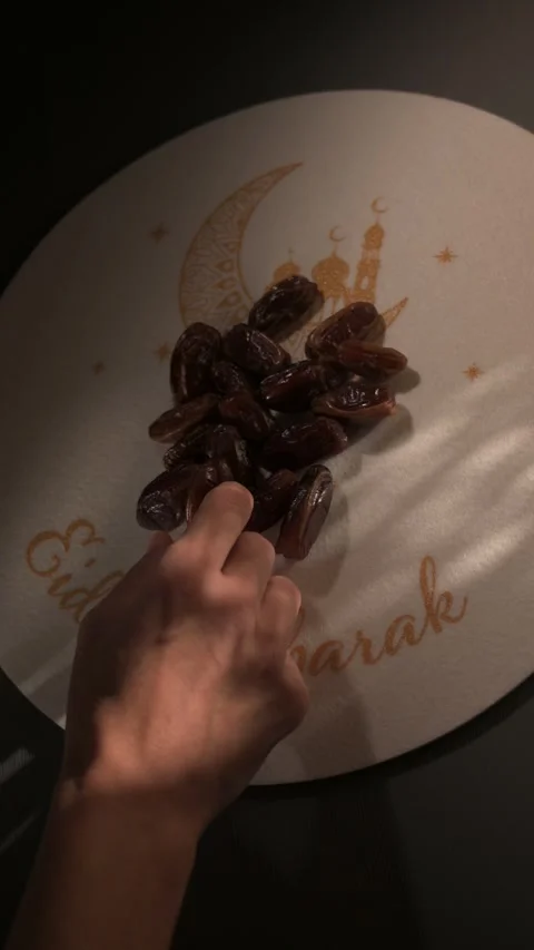 Hand taking a date from an Eid Mubarak plate during Ramadan Stock Footage 328337148