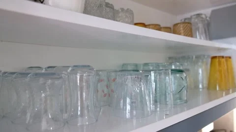 Hand Taking Glass from Shelf Inside Kitchen Cabinet with Two Rows of Glasses Stock Footage 302688075