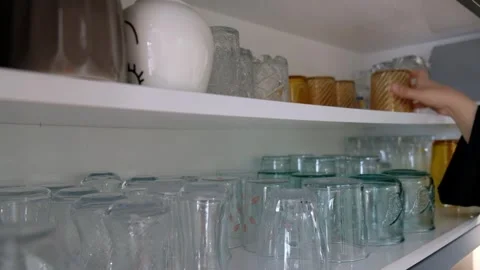 Hand Taking Glass from Shelf Inside Kitchen Cabinet with Two Rows of Glasses Stock Footage 302688089
