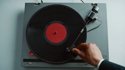Hand taking gramophone tonearm starting music playing in apartment closeup. Stock Footage 332622968