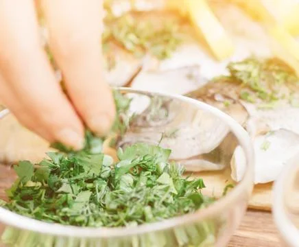 Hand taking greenery for fish dish, close-up. Stock Photos