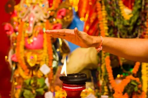 A hand taking heat of the flame as blessing from a lit clay lamp on top of a  Stock Photos