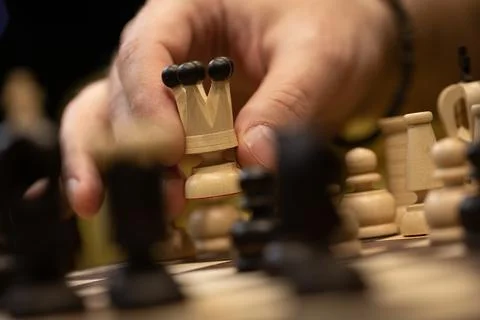 Hand taking next step on chess game. Human hand moving wooden white queen piece Stock Photos