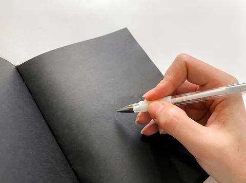 Hand taking notes in a notebook with black sheets.Planning concept Stock Photos
