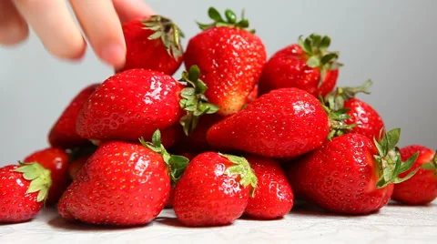 Hand taking One strawberry on white kitchen background Stock Footage 63226334