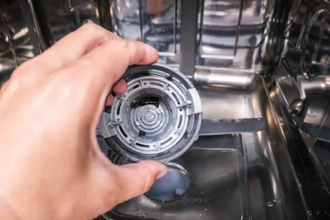 A hand taking out dishwasher filter to clean it, dis washer cleaning concept Stock Photos