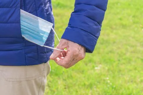 Hand taking out of jacket pocket protective face mask Stock Photos