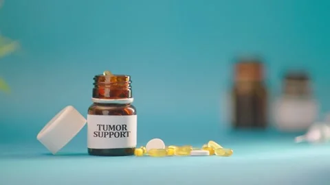 HAND TAKING OUT TUMOR SUPPORT TABLETS FROM MEDICINE BOTTLE Stock Footage 308111382