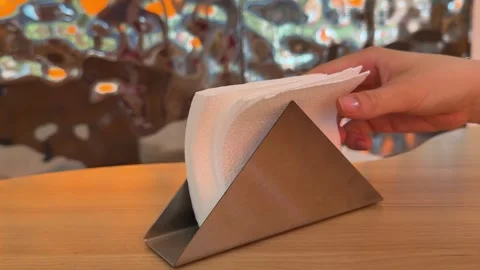 Hand taking a paper napkin from a tabletop napkin holder on a wooden table Stock Footage 345181019