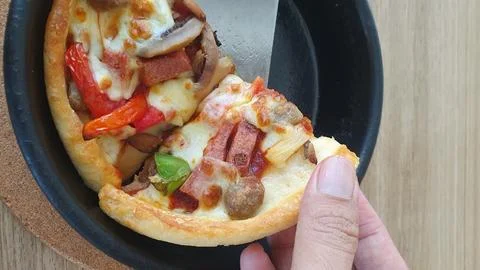 Hand taking personal pizza slice Fotos Stock