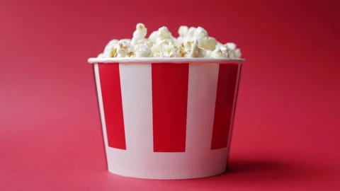  hand taking popcorn from striped red and white paper box  Stock Footage 126570396