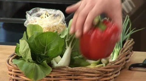 Hand taking red pepper &amp; carrot out of basket of vegetables Stock Footage 24633712