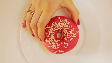 Hand taking red, pink donut from white plate, view from above Video stock 124254253