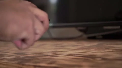 Hand taking remote control from wooden table surface, 库存影片 343843159
