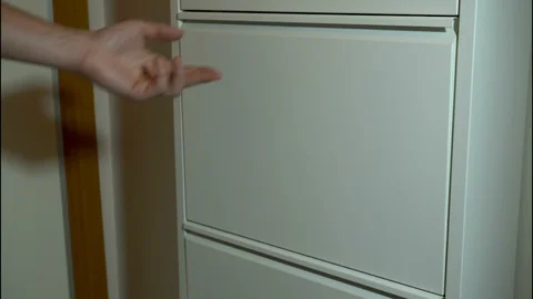 A Hand is taking shoes off a Layered Mechanical Shoe Cabinet Stock Footage 129837442