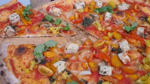 Hand taking a slice of vegan pizza topped with lots of vegetables and plant and Stock Footage 148544653