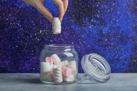 Hand taking soft marshmallow piece from glass jar Stock Photos