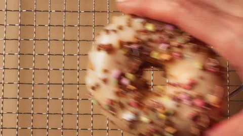 Hand Taking Sprinkle Donut from Cooling Rack Display Stock Footage 331233590
